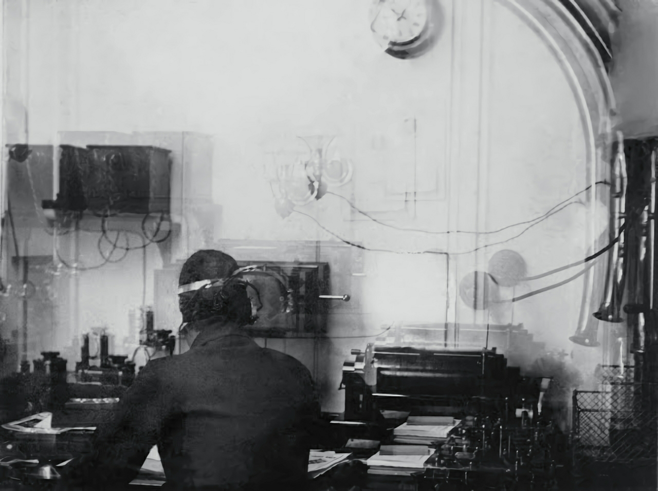 Titanic's Marconi wireless room with radio equipment and an operator seated at the desk.